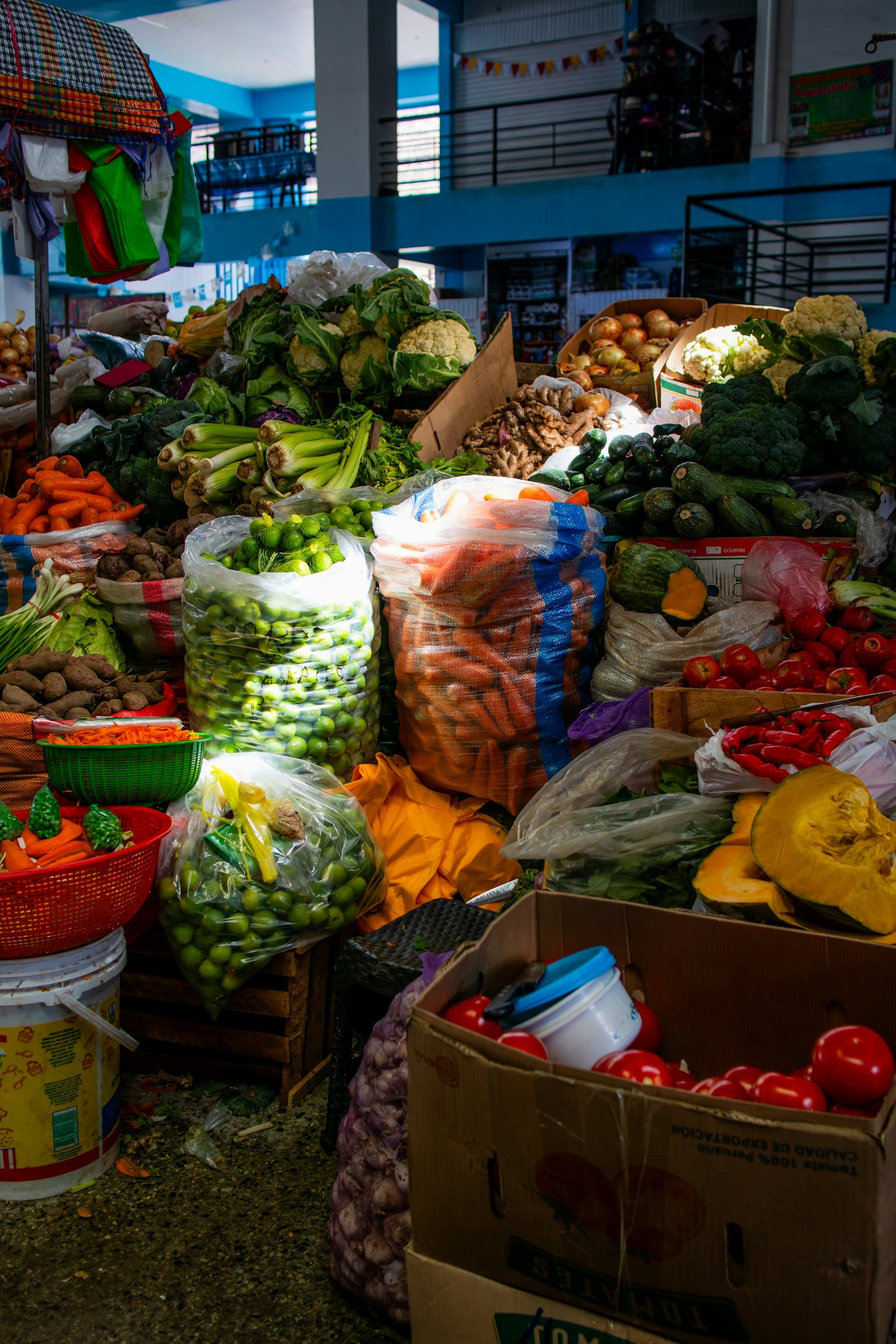A market stall stacked with vegetables, herbs and sacks of produce.